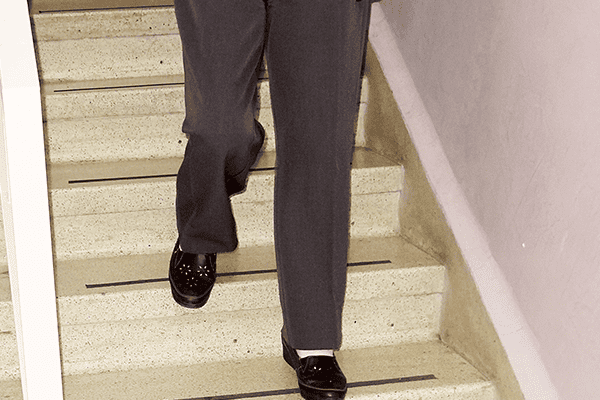 Paciente bajando las escaleras con dolor de rodilla por síntomas de la artrosis de rodilla